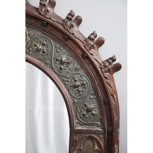 543 - A LATE 19TH CENTURY 'GOTHIC' OAK AND BRASS WALL MIRROR. the carved arched surround to pressed brass ... 
