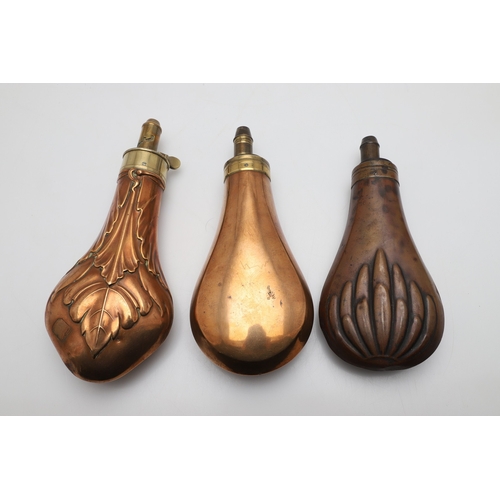 65 - A COLLECTION OF THREE LARGE COPPER BODIED POWDER FLASKS. A copper bodied powder flask, the body deco... 