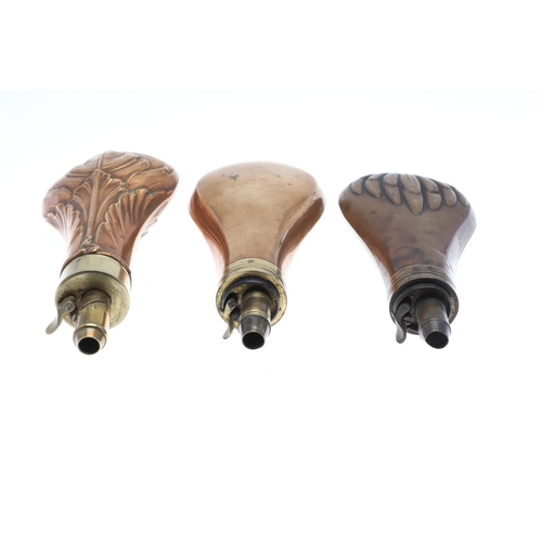 65 - A COLLECTION OF THREE LARGE COPPER BODIED POWDER FLASKS. A copper bodied powder flask, the body deco... 