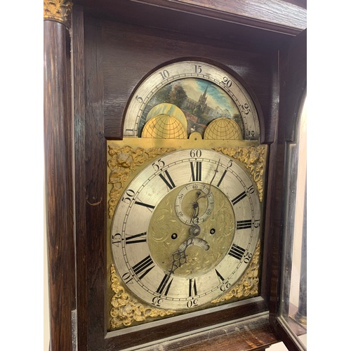 123 - OAK CASED LONG CASE CLOCK WITH ROCKING ARCH DIAL DEPICTING CATHEDRAL BRASS FACE AND SPANDRELS SILVER... 