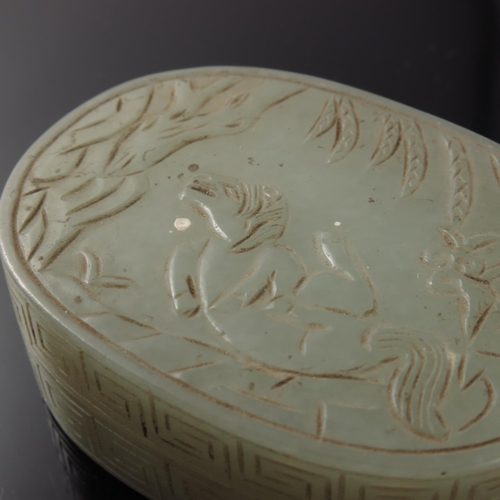 471 - CHINESE JADE BOX AND COVER OF OVAL FORM, THE COVER CARVED WITH A MYTHICAL CREATURE, TREES AND FOLIAG... 