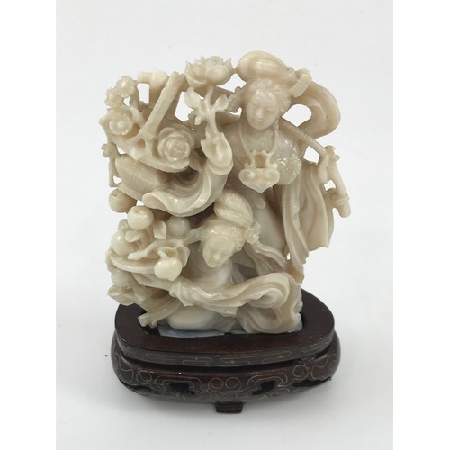 1968 - CARVED OPAL FIGURE GROUP DEPICTING 2 LADIES WITH FLOWERS APPROX 10 cm ON HARDWOOD PRESENTATION STAND