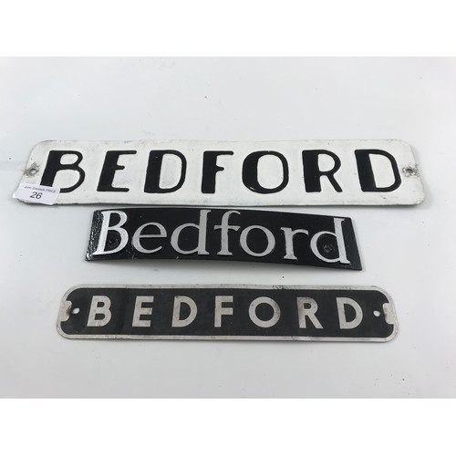 26 - 3 BEDFORD BADGES : A PRESSED PLATE BEDFORD BLACK WRITING ON WHITE BACKGROUND, A CAST BEDFORD RADIATO... 