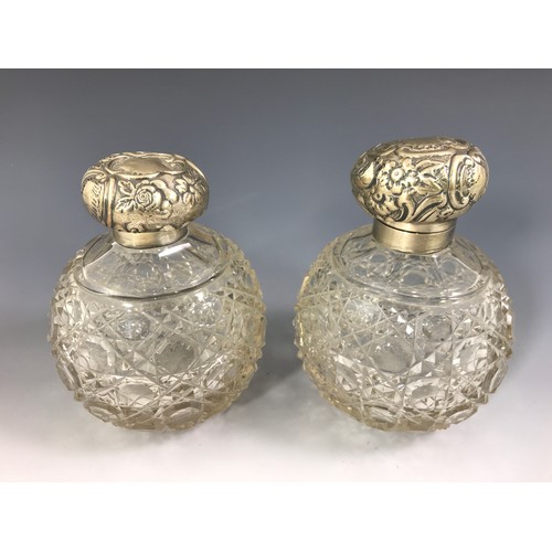 3352 - PAIR OF CUT GLASS SILVER TOP PERFUME BOTTLES EACH APPROX. 14 cms WITH REPOUSSE DECORATED HINGED SILV... 