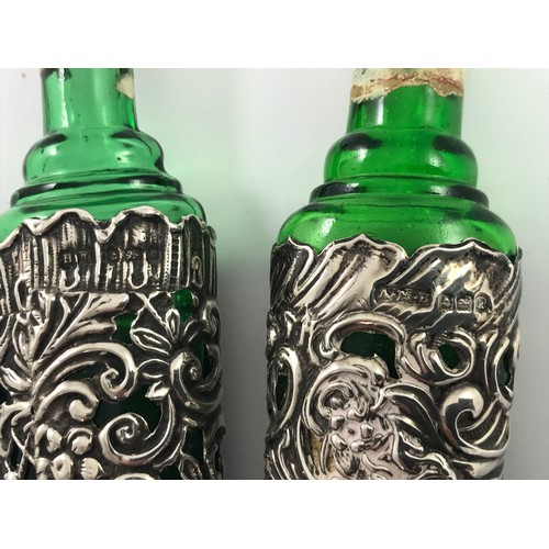 413 - 2 GREEN GLASS FLASKS WITH EMBOSSED SILVER COVERS, LARGEST APPROX. 22 cm