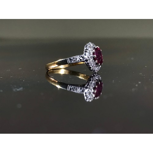 492 - 18ct GOLD RING SET WITH AN OVAL RUBY WITHIN A RING OF DIAMONDS