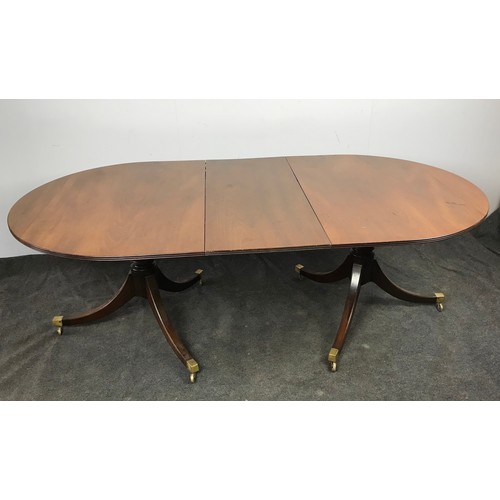 267 - TWIN PEDESTAL REGENCY STYLE MAHOGANY DINING TABLE HAVING BRASS CAPS AND CASTERS TO EACH OF THE PEDES... 