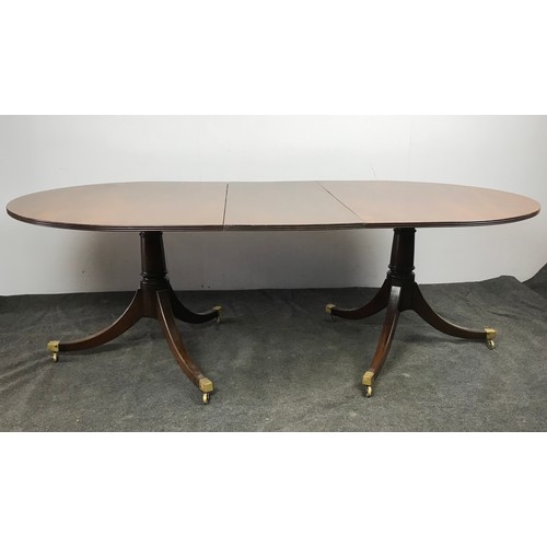 267 - TWIN PEDESTAL REGENCY STYLE MAHOGANY DINING TABLE HAVING BRASS CAPS AND CASTERS TO EACH OF THE PEDES... 