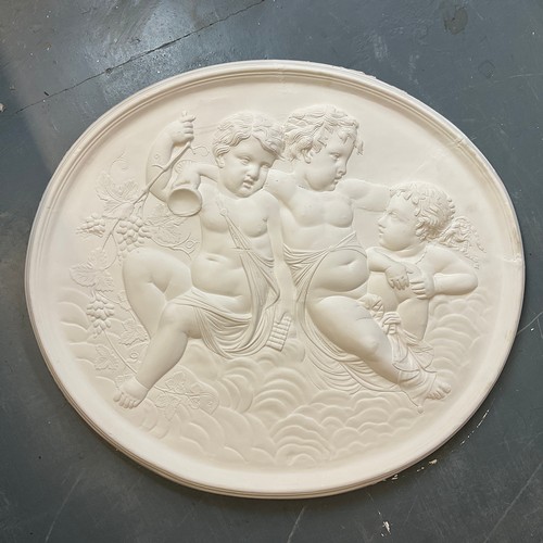 265 - AN OVAL PLASTER PANEL, RELIEF MOULDED DECORATION DEPCIGTING THREE PUTTI WITH FRUITING VINES, 78CM WI... 