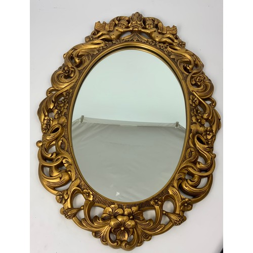 67 - A GILT PLASTER FRAMED WALL MIRROR WITH PUTTI AND RETICULATED BORDER