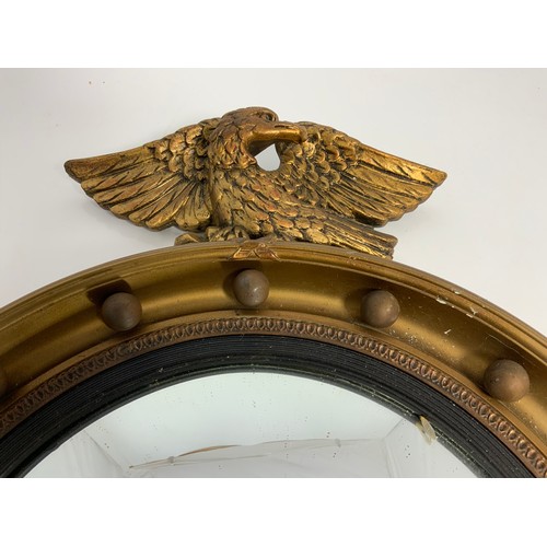 63 - ROUND CONVEX MIRROR WITH GILT FRAME, APPLIED BALL DECORATION AND EAGLE FINIAL, APPROX. 41 cm dia.