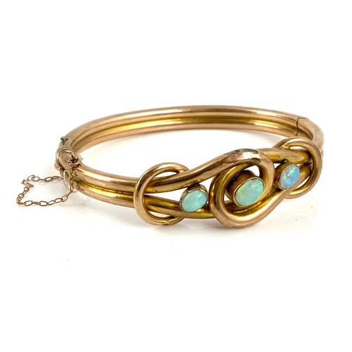 558 - A 9CT GOLD HINGED BANGLE WITH KNOT DESIGN SET WITH 3 OVAL OPALS,APPROX. 12g GROSS