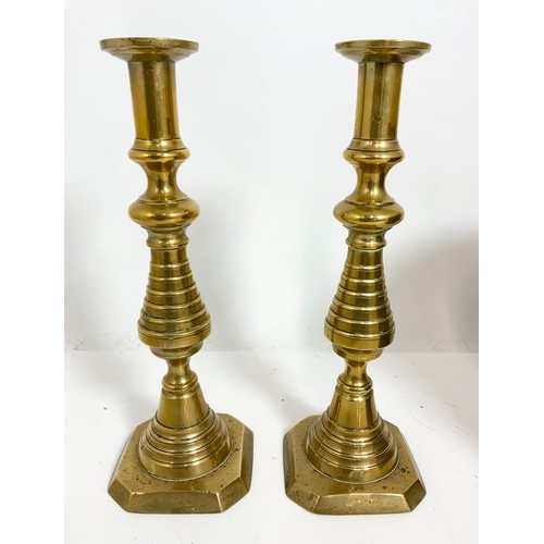 310 - A PAIR OF 31cm TALL BRASS CANDLESTICKS WITH PUSHERS,  A COAL SCUTTLE AND A CANON BALL