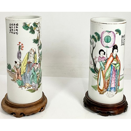 63 - PAIR OF CYLINDRICAL ORIENTAL VASES ON HARDWOOD STANDS EACH DEPICTING FIGURES AND WITH ORIENTAL SCRIP... 