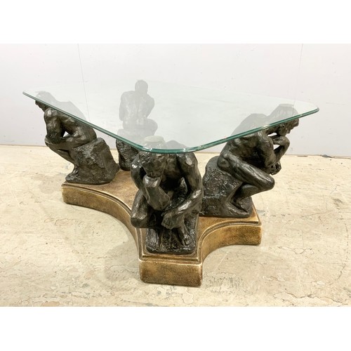 671 - A GLASS TOP COFFEE TABLE SUPPORTED ON FOUR 'THE THINKER' FIGURES