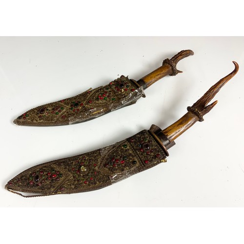 130 - 2 ANTLER HANDLED KUKRI EACH WITH A JEWEL ENCRUSTED SHEATH