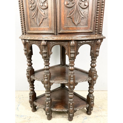 596 - STANDING OAK CORNER CUPBOARD WITH CARVED FLEMISH STYLE DECORATION 170cm TALL