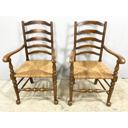 678 - A PAIR OF LADDER BACK CARVER / ARM CHAIRS WITH RUSH SEATS