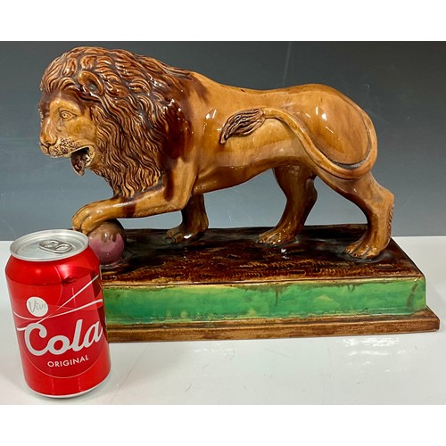 94 - 19TH CENTURY MAJOLICA LION FIGURE ON PLINTH, ITS FRONT PAW RESTING ON A PINK BALL. Approx. 36cm L x ... 