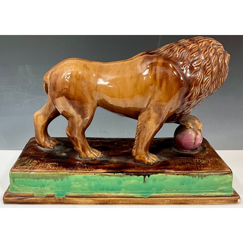 94 - 19TH CENTURY MAJOLICA LION FIGURE ON PLINTH, ITS FRONT PAW RESTING ON A PINK BALL. Approx. 36cm L x ... 