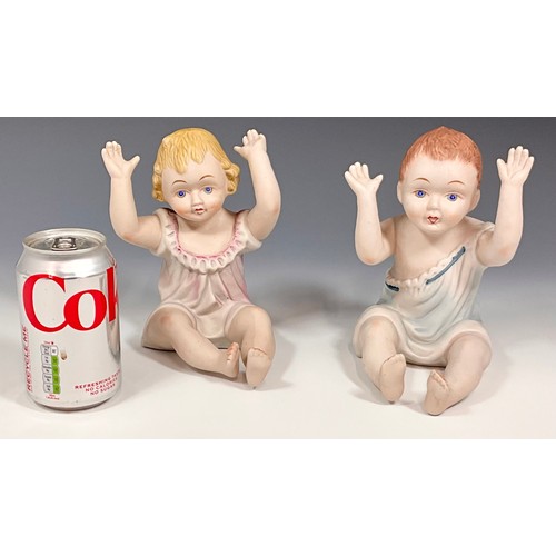 105 - A PAIR OF SEATED BISQUE PIANO BABIES, BOY AND GIRL