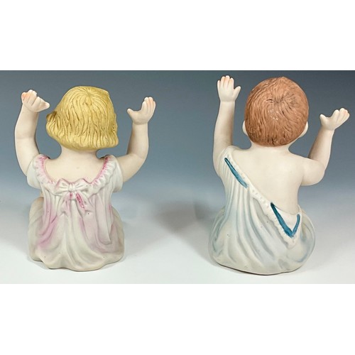 105 - A PAIR OF SEATED BISQUE PIANO BABIES, BOY AND GIRL