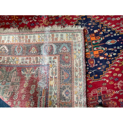 749 - LARGE HAND KNOTTED PERSIAN STYLE RED GROUND RUG, THREE CENTRAL LOZENGES, DECORATED WITH HORSES, GOAT... 