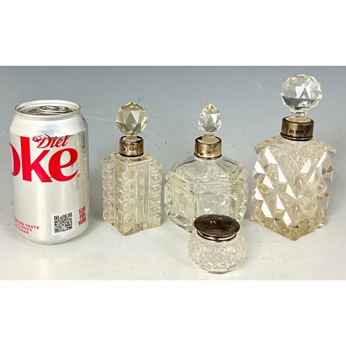 236 - THREE CUT GLASS PERFUME BOTTLES WITH SILVER COLLARS AND A SILVER TOP DRESSING TABLE POT