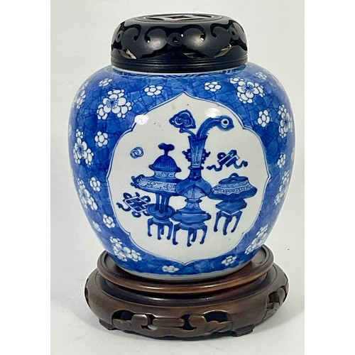 127 - A CHINESE BLUE AND WHITE GINGER JAR DECORATED WITH 3 PANELS HAVING PIERCED HARDWOOD COVER ON A HARDW... 