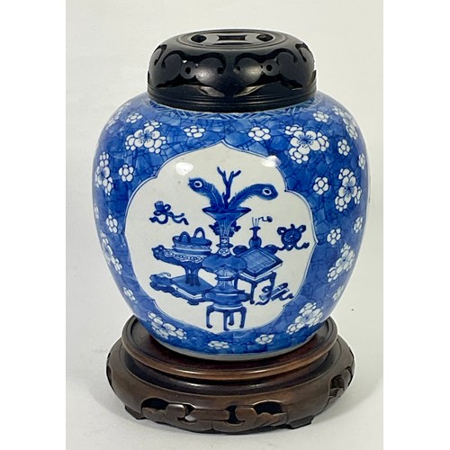 127 - A CHINESE BLUE AND WHITE GINGER JAR DECORATED WITH 3 PANELS HAVING PIERCED HARDWOOD COVER ON A HARDW... 