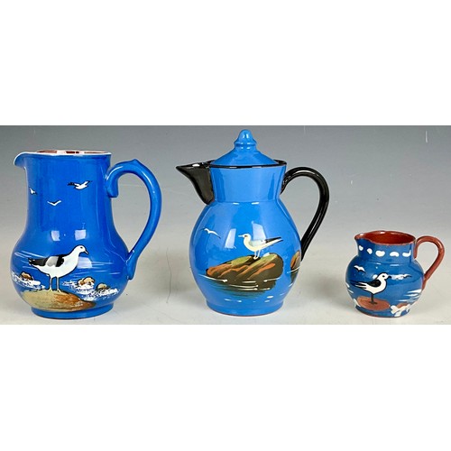 191 - HAND PAINTED STUDIO POTTERY TEAPOT AND TWO JUGS OF SIMILAR DESIGN DECORATED WITH SEAGULLS