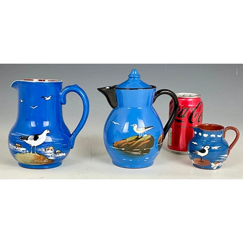 191 - HAND PAINTED STUDIO POTTERY TEAPOT AND TWO JUGS OF SIMILAR DESIGN DECORATED WITH SEAGULLS