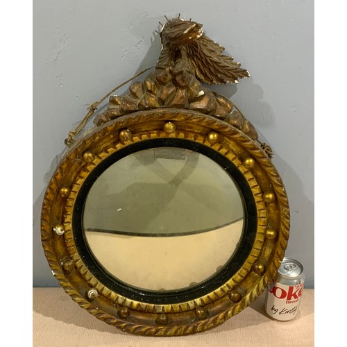 75 - CONVEX GILT FRAME MIRROR WITH MUSKET BALL AND A EAGLE FINIAL  DECORATION AF 43cm DIAMETER