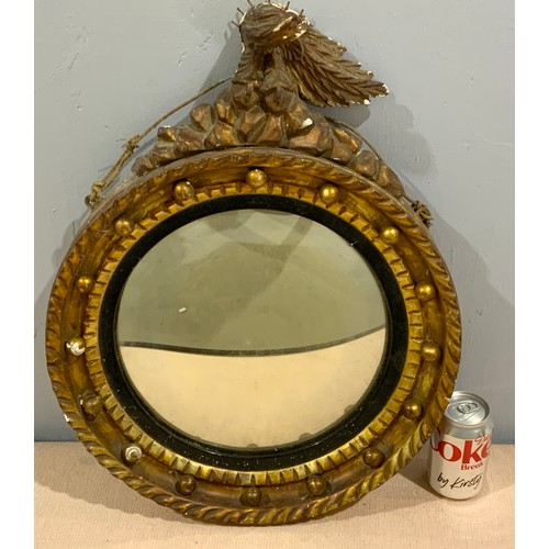 75 - CONVEX GILT FRAME MIRROR WITH MUSKET BALL AND A EAGLE FINIAL  DECORATION AF 43cm DIAMETER