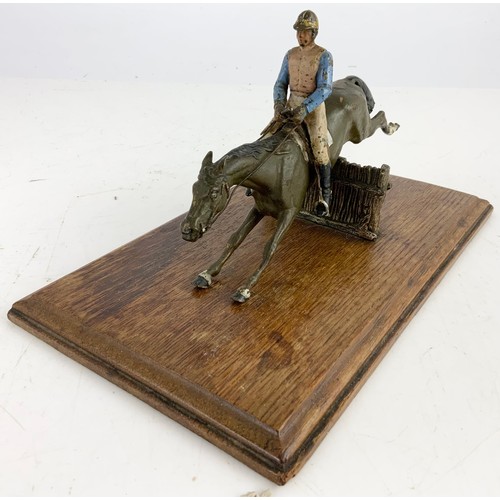 358 - A COLD PAINTED METAL WALL MOUNTING LETTER CLIP MODEL AS A HORSE AND JOCKEY JUMPING A FENCE ON AN OAK... 