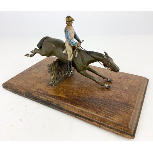 358 - A COLD PAINTED METAL WALL MOUNTING LETTER CLIP MODEL AS A HORSE AND JOCKEY JUMPING A FENCE ON AN OAK... 