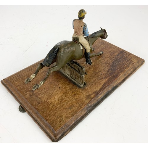 358 - A COLD PAINTED METAL WALL MOUNTING LETTER CLIP MODEL AS A HORSE AND JOCKEY JUMPING A FENCE ON AN OAK... 