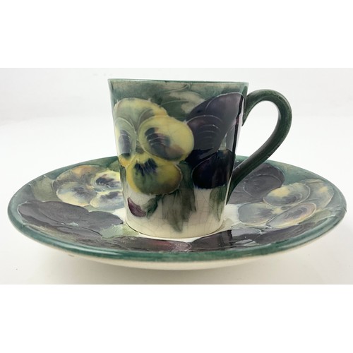18 - RARE EARLY MOORCROFT POTTERY COFFEE CAN / CUP AND SAUCER DECORATED WITH PANSY PATTERN ON A WHITE  GR... 