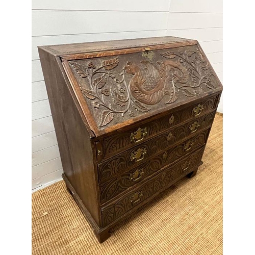 115 - A heavy carved bureau, the fall front enclosing interior fitted drawers and pigeon holes with four l... 