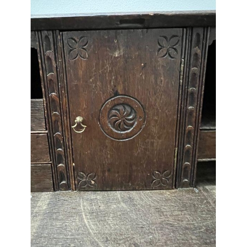 115 - A heavy carved bureau, the fall front enclosing interior fitted drawers and pigeon holes with four l... 
