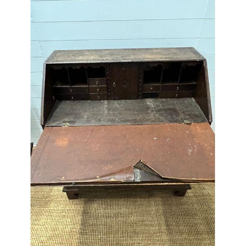 115 - A heavy carved bureau, the fall front enclosing interior fitted drawers and pigeon holes with four l... 