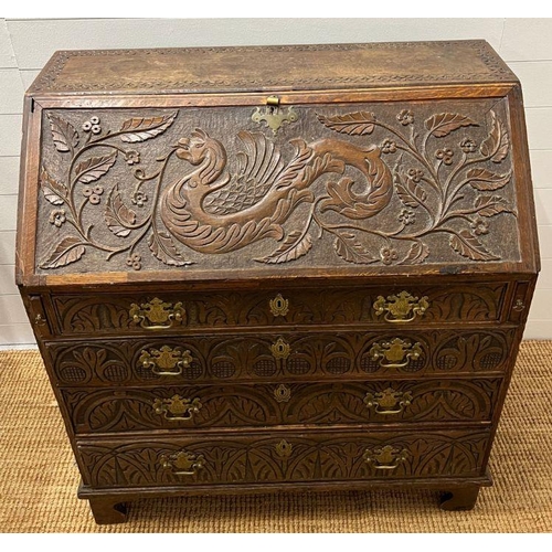 115 - A heavy carved bureau, the fall front enclosing interior fitted drawers and pigeon holes with four l... 