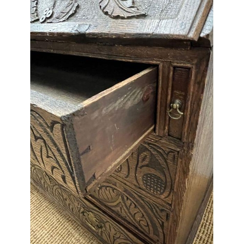 115 - A heavy carved bureau, the fall front enclosing interior fitted drawers and pigeon holes with four l... 