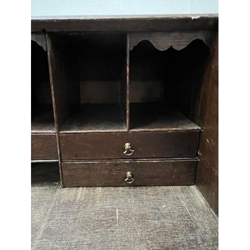 115 - A heavy carved bureau, the fall front enclosing interior fitted drawers and pigeon holes with four l... 