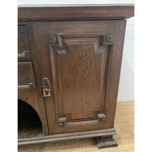 134 - An Arts and Crafts style sideboard, two central drawers flanked by cupboards on square turned feet (... 