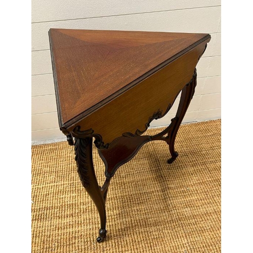 150 - A tri-form side table with scrolling edges and legs terminating on castors