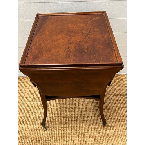151 - A mahogany side table with hinged sides on down swept legs and castors (H69cm W52cm D48cm)