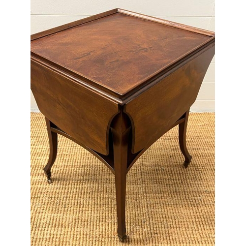 151 - A mahogany side table with hinged sides on down swept legs and castors (H69cm W52cm D48cm)