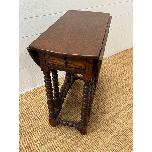 164 - An oak gate leg table with drawer to centre