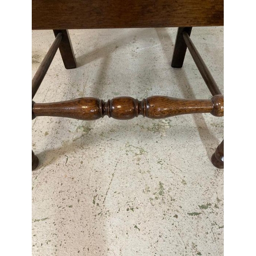 176 - An oak spool turned ladder back arm chair upholstered in red